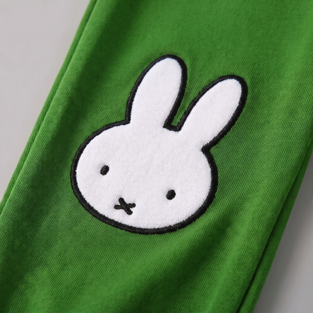 Detalle de diseño del conjunto de salón de bambú «Move» en Miffy, con sudadera con motivo de bicicleta y pantalones de chándal verdes.